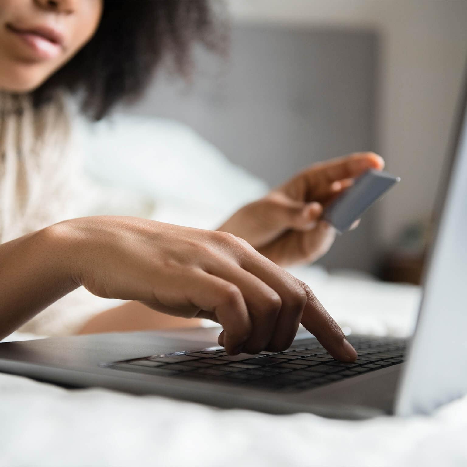 Woman laying in bed online shopping with laptop