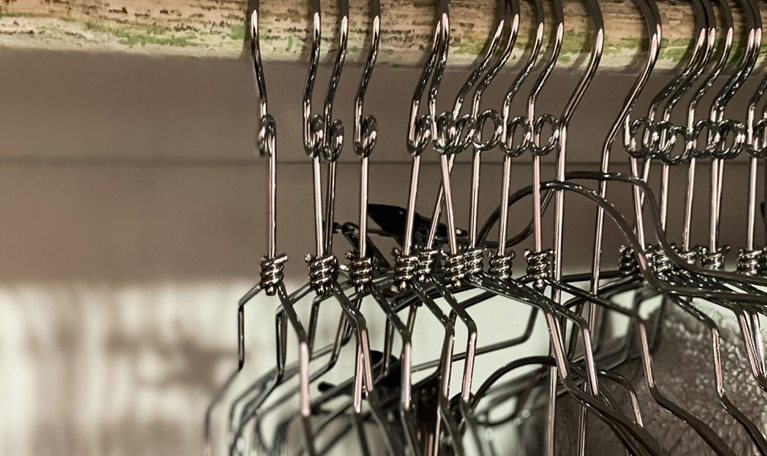 Empty metal clothing hangers in closet - stock photo