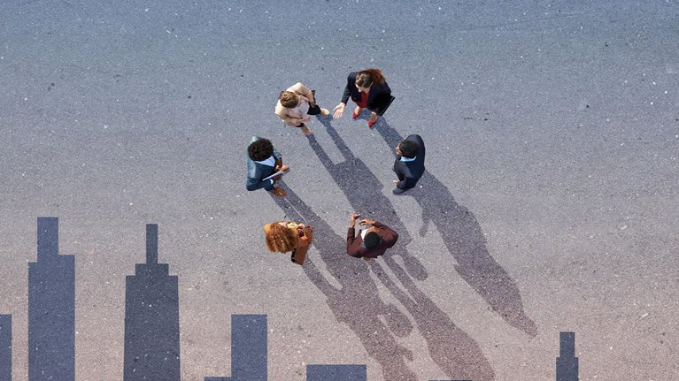 Group of young adults, photographed from above, standing on asphalt painted with skyline, at sunrise. - stock photo