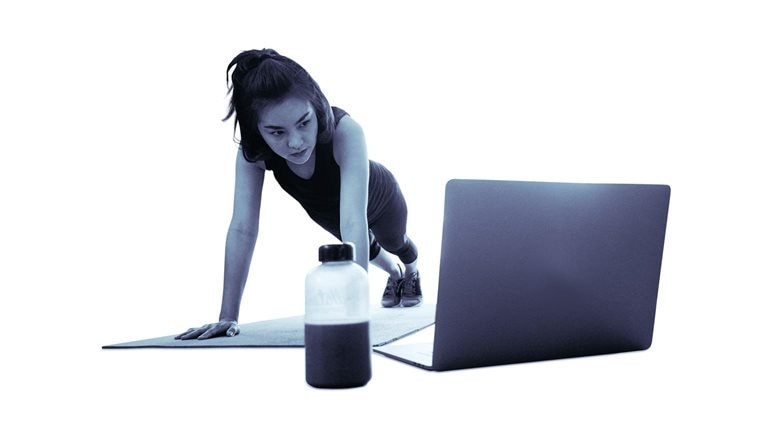 Woman doing a push up next to a laptop