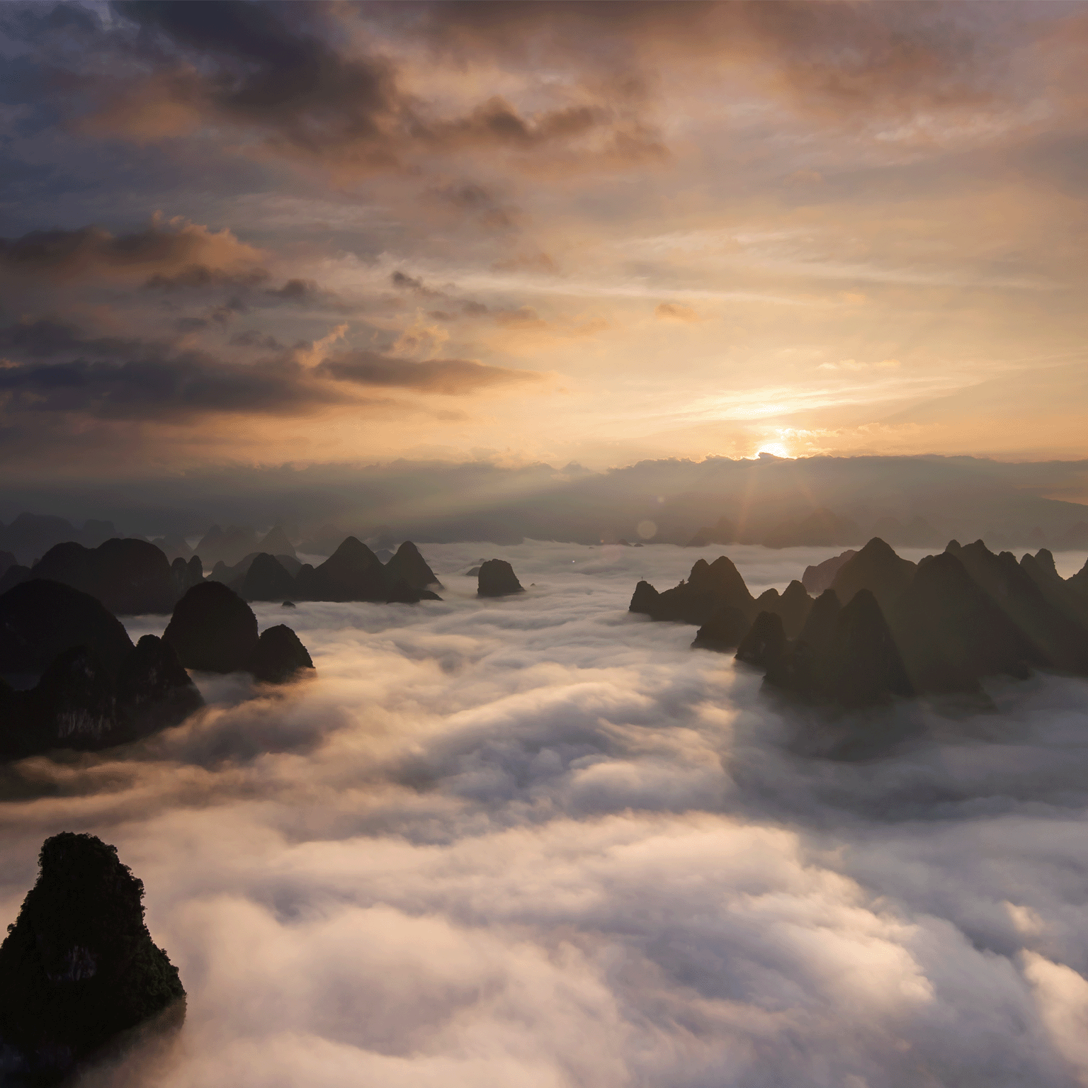 photo sun rising behind mountain, clouds in foreground
