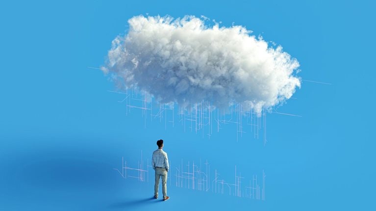 A business man looking up at a fluffy white cloud with digital lines radiating from it.