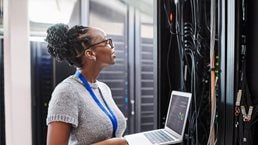 Shot of a young woman using a laptop in a server room - stock photo