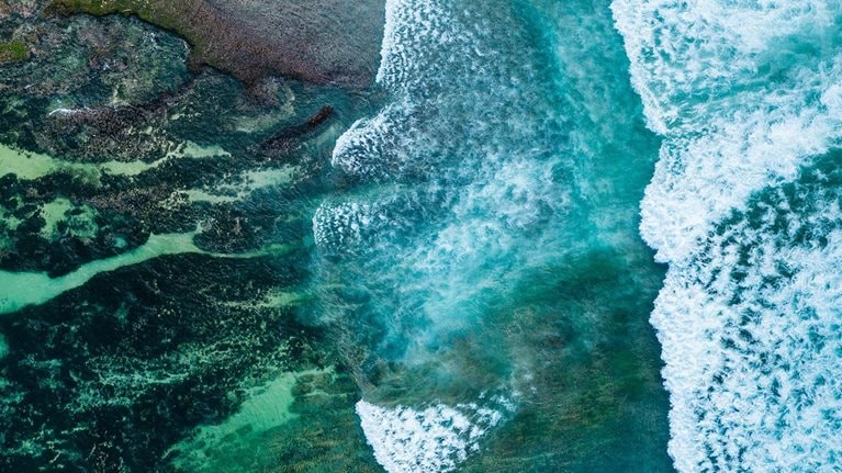 Big ocean waves hitting a coral reef. View from above. - stock photo