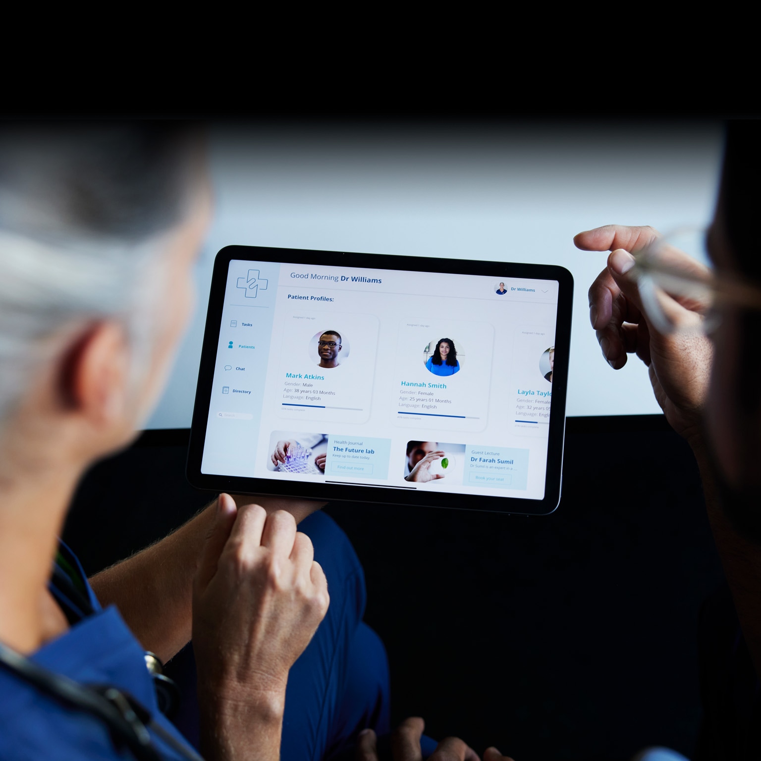 Two doctors looking at patient data on digital tablet - stock photo