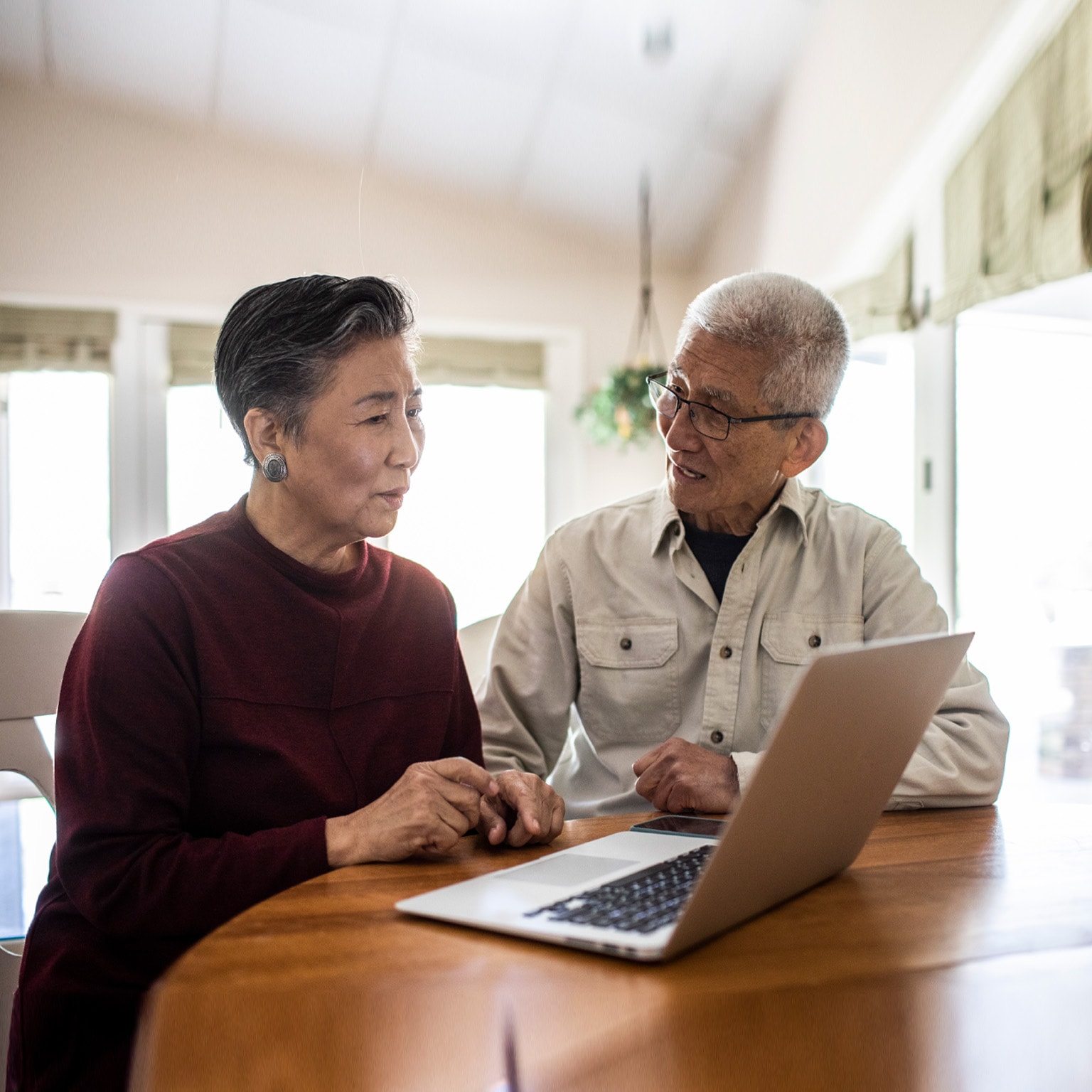 elderly couple talking in front of open laptop
