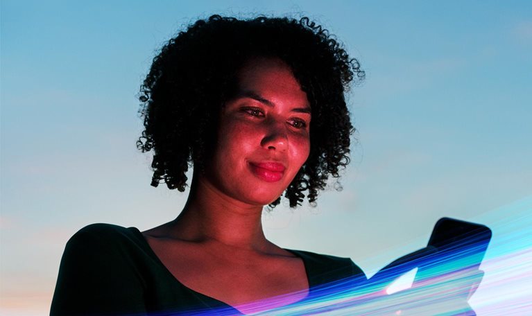 Woman using a smartphone against a vibrant blue sky backdrop, surrounded by vivid streaks of colorful light.