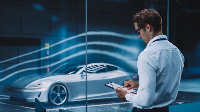 Engineering Research Agency Perform Aerodynamic Testing with a Modern Eco-Friendly Electric Sports Car in a Wind Tunnel. Professional Scientist Works on a Tablet Computer and Changes Testing Options.