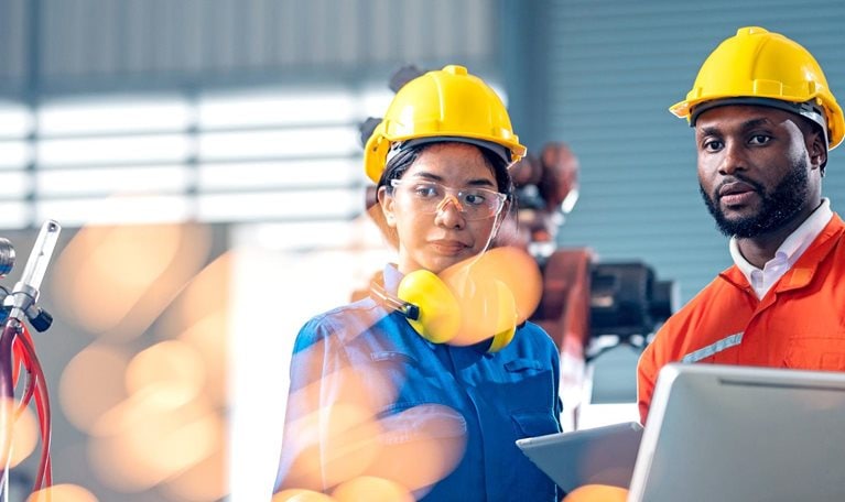 Two engineers having a meeting in front of industrial robots welder in production line.