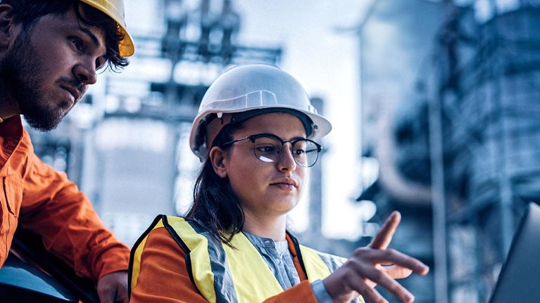 Two engineers, man and woman, using laptop to work at power plant on night shift