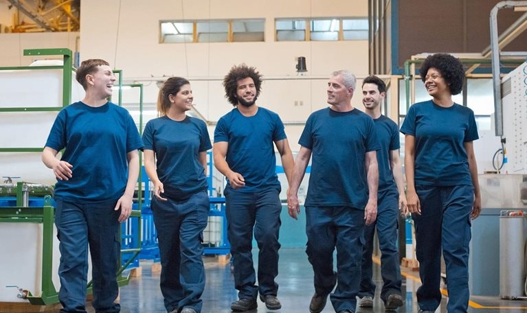 Front view of group of blue-collar workers walking in factory.