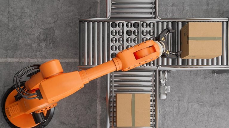 Top view of robotic arm working on conveyor belt In smart warehouse.