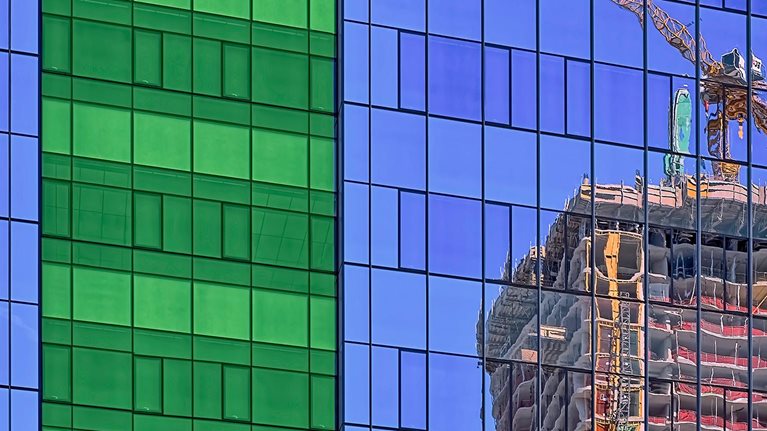 reflection of crane in glass on side of building stock photo