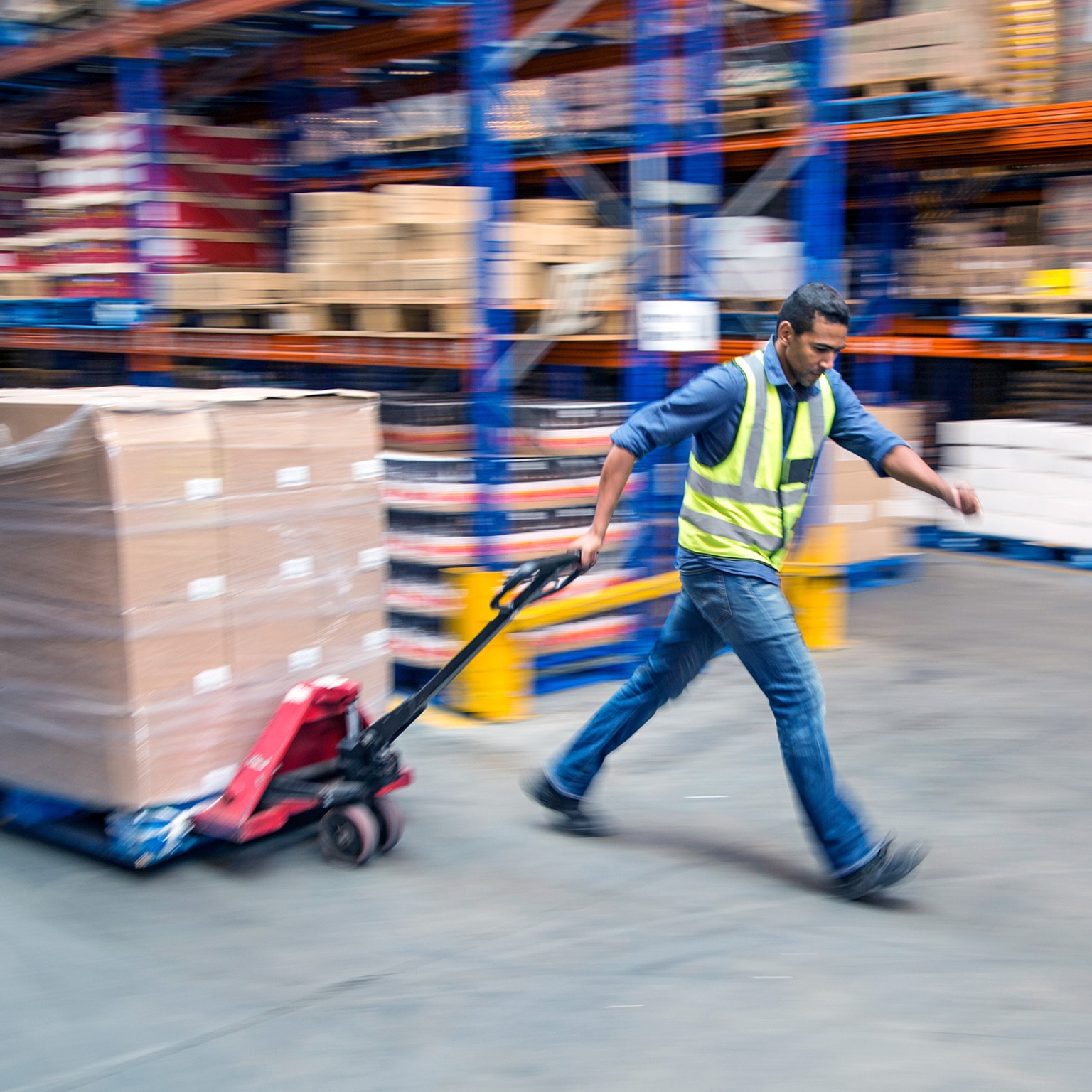 Worker pulling pallet truck inside a food distribution warehouse
