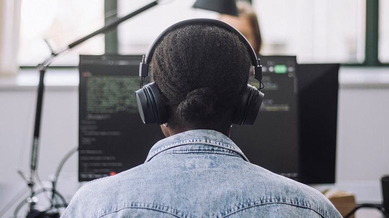 Rear view of female computer programmer coding on computer at desk in office - stock photo