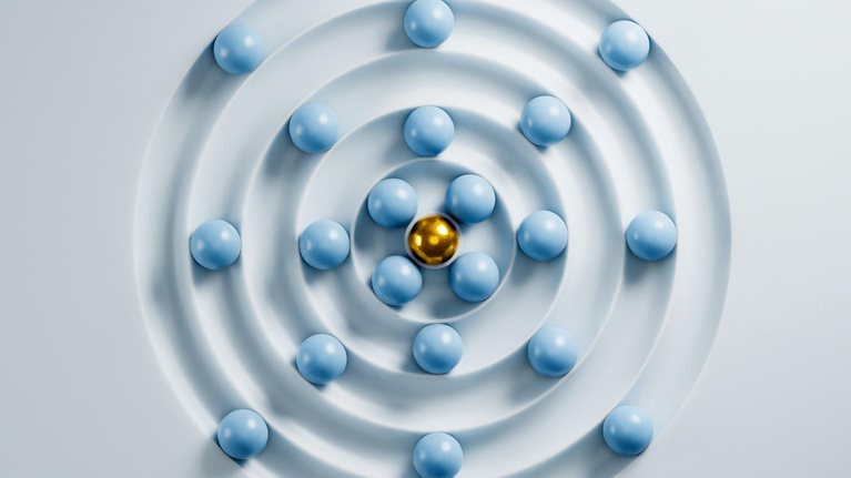 Golden sphere leading many light blue spheres in a concentric circle pattern