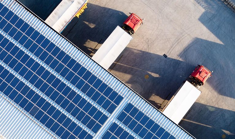 Truck loading in warehouse, solar panels on factory rooftop - stock photo