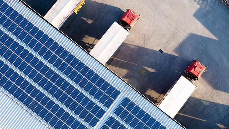 Truck loading in warehouse, solar panels on factory rooftop - stock photo