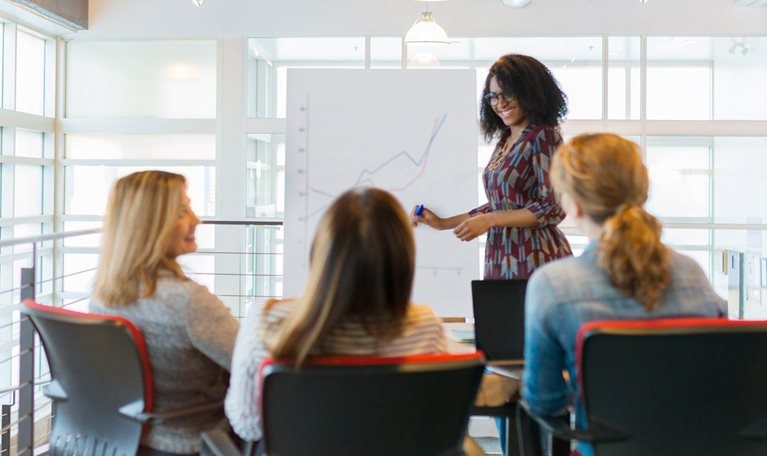 Businesswoman leading meeting at flip chart in conference room - stock photo