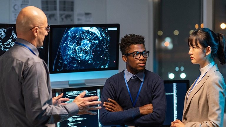 Three intercultural colleagues in formalwear discussing working points at meeting