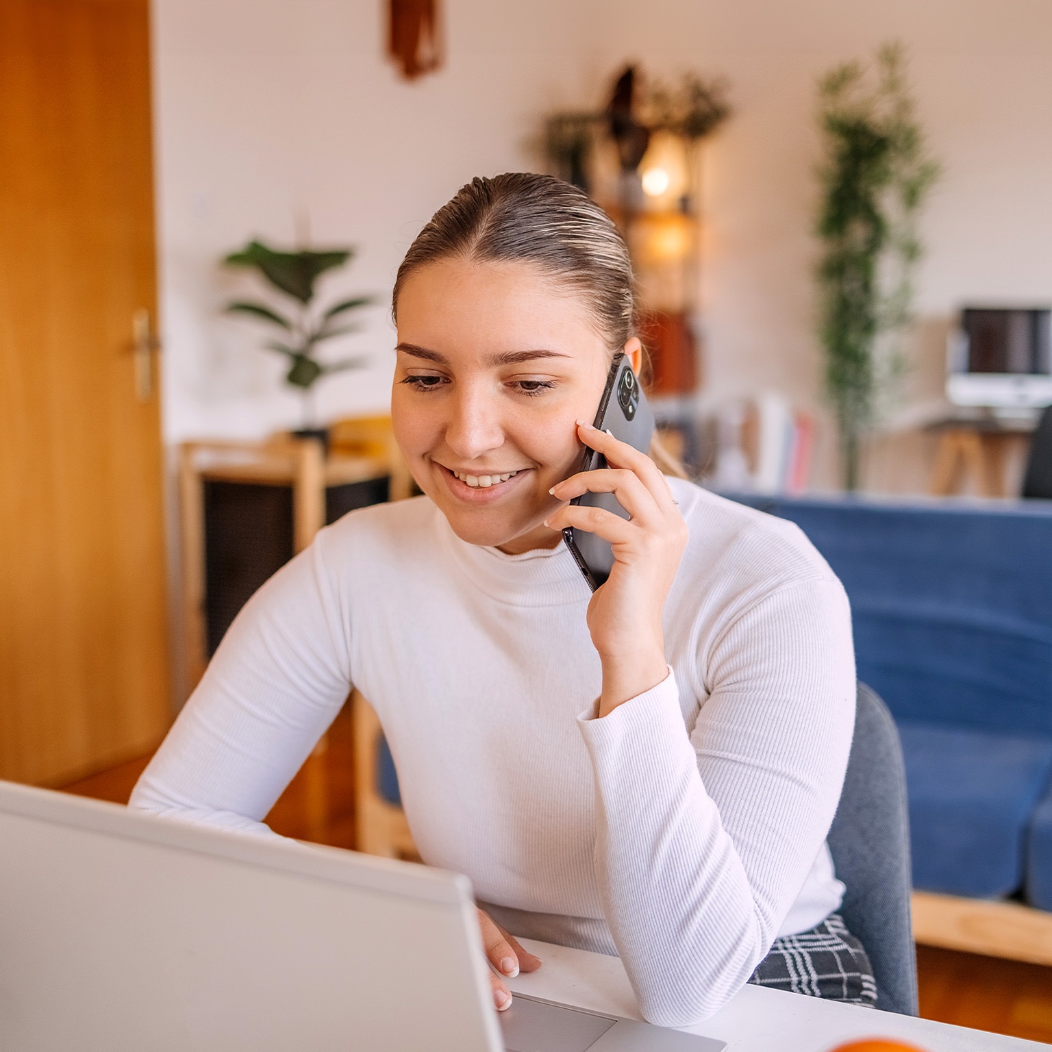 Young woman making on line order from home using mobile phone and laptop - stock photo