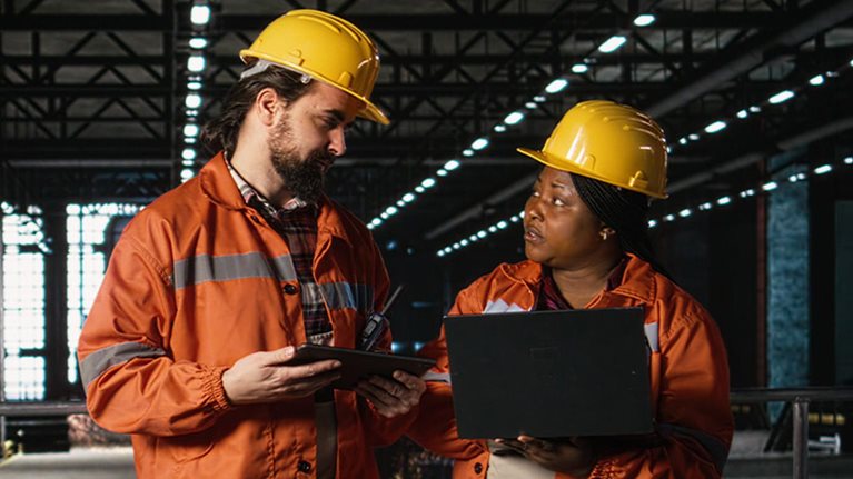 Engineering team reviewing steel work and heavy equipment in industrial space
