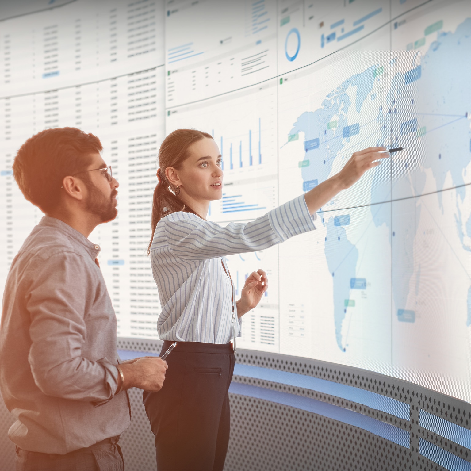Diverse colleagues, data scientist and business manager, discussing objectives talking in front of big digital screen with graphs, charts and map in monitoring office. - stock photo