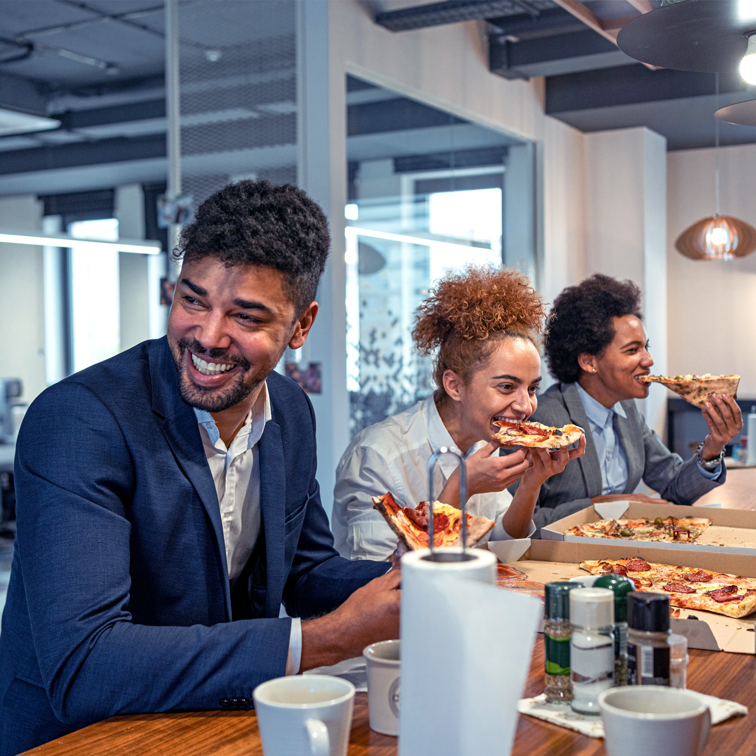Multiracial group of business people, eating a pizza for their lunch break at cafeteria