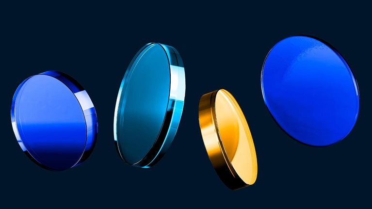 Four glass like discs in shades of blue and gold float in a row against a dark background.