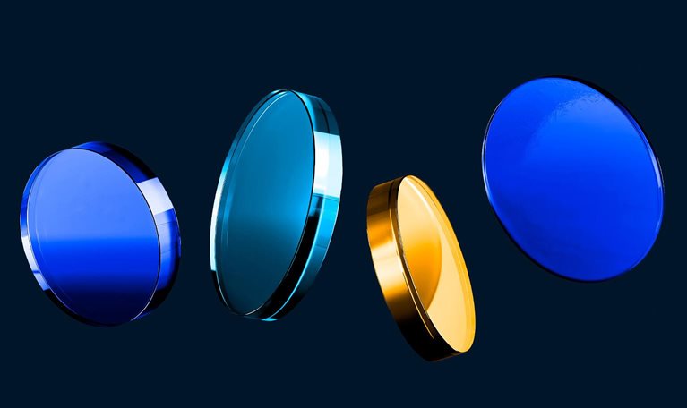 Four glass like discs in shades of blue and gold float in a row against a dark background.