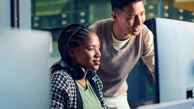 Software engineers huddled over a computer screen, collaborating on a project