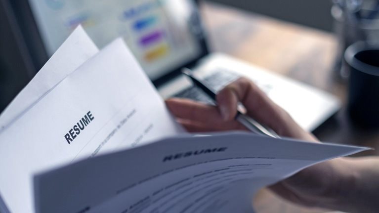 HR employee flipping through a stack of printed resumes