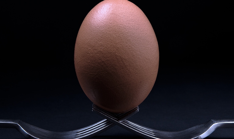 A brown egg balanced on two forks