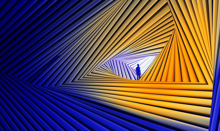 A small silhouetted figure stands inside a glowing triangular opening formed by repeating blue and orange geometric lines, creating the impression of looking through a futuristic tunnel or portal.