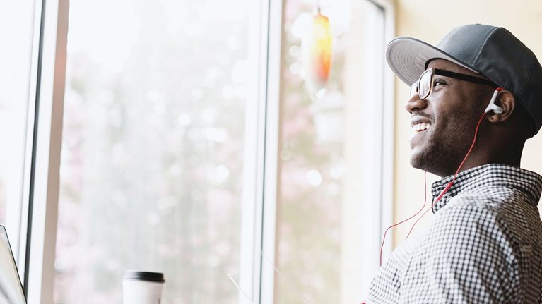 Laughing man using laptop in coffee shop