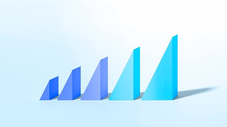 Colorful triangle shapes on pastel background increasing in size to illustrate growth