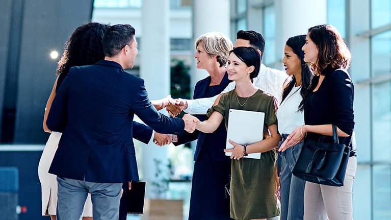 A group of businesspeople greeting each other inside of a office