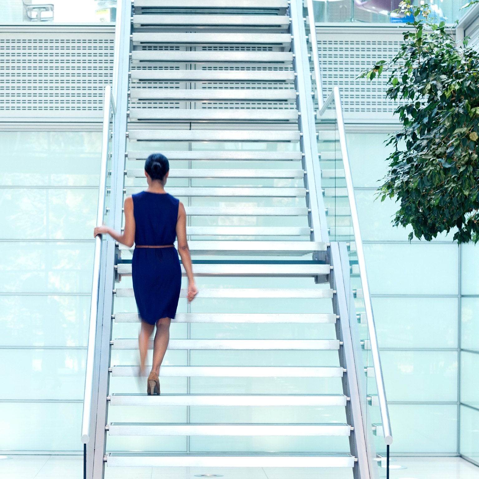 Businesswoman walking up staircase in modern lobby
