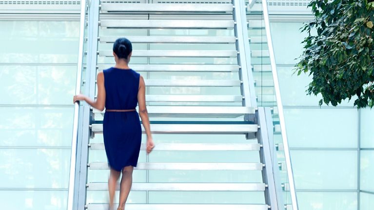 Businesswoman walking up staircase in modern lobby