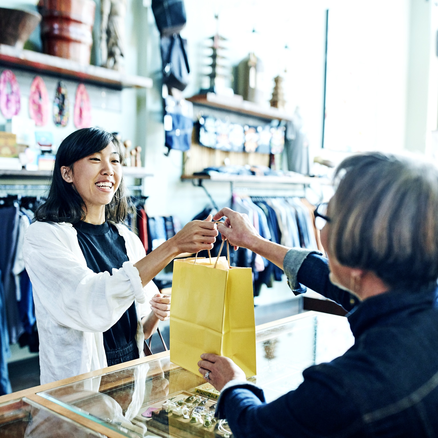 A shop worker handing a bag to a smiling client