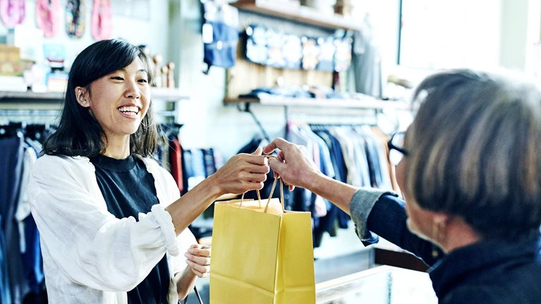 A shop worker handing a bag to a smiling client
