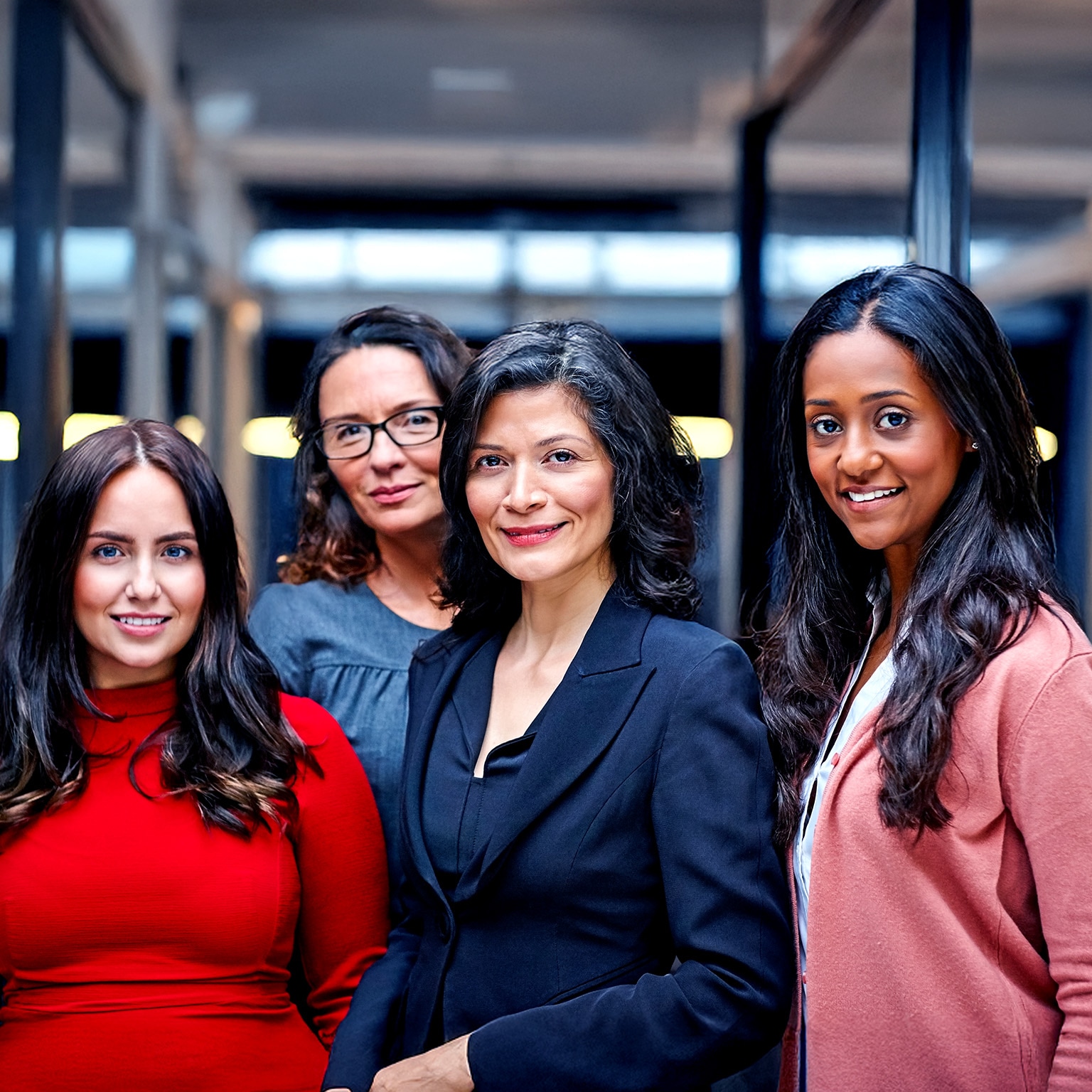 A diverse group of four professional women look confidently forward.