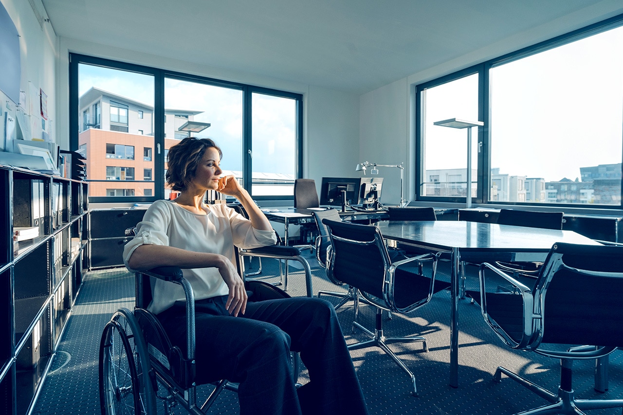 A woman in a wheelchair is looking out the window.
