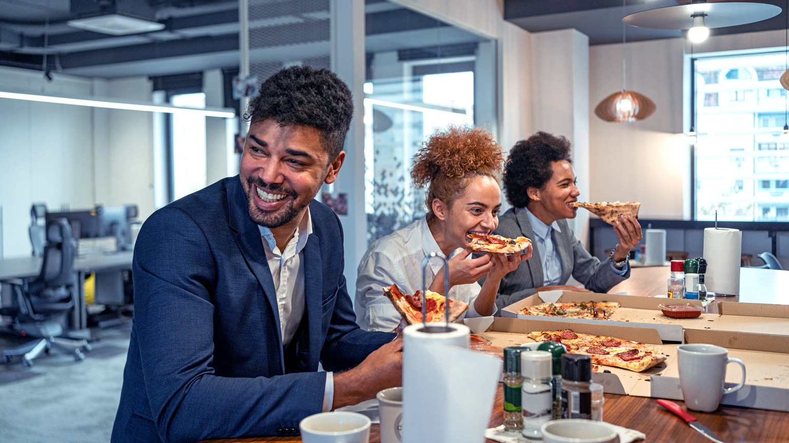 Multiracial group of business people, eating a pizza for their lunch break at cafeteria