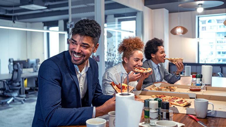Multiracial group of business people, eating a pizza for their lunch break at cafeteria