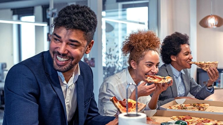 Multiracial group of business people, eating a pizza for their lunch break at cafeteria