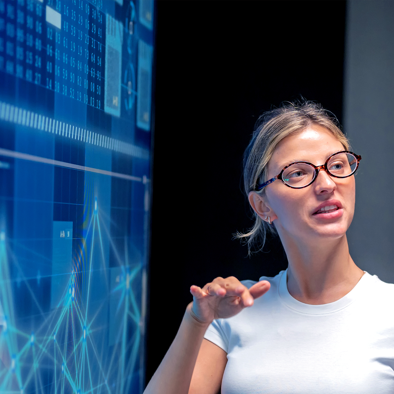 Business meeting in modern office with female programmer explaining infographic on screen to Japanese manager. Teamwork, strategy, innovation, coding, big data, AI, and technology presentation for success