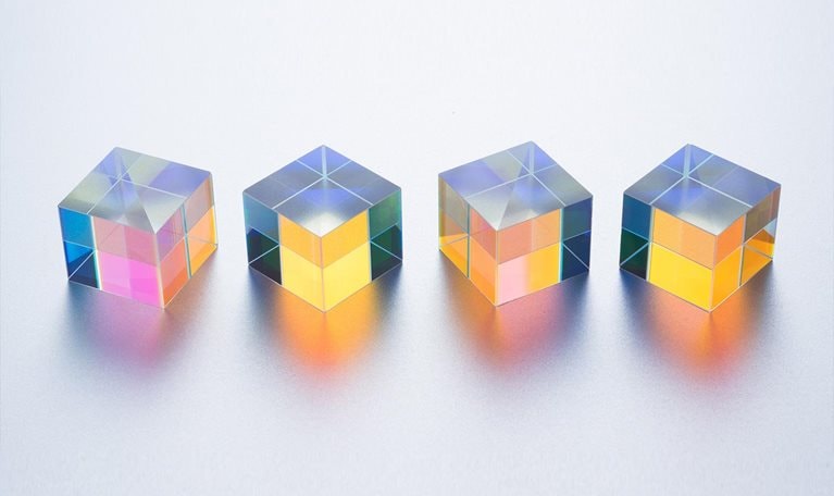 Four X-cube Prisms in a Row on Silver Background Close-up View - stock photo