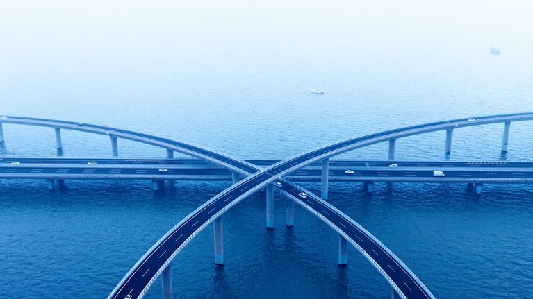Aerial view of intersecting highway bridges over water with light traffic.
