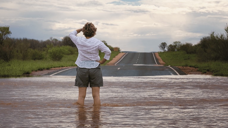 Woman stands in flooded street.